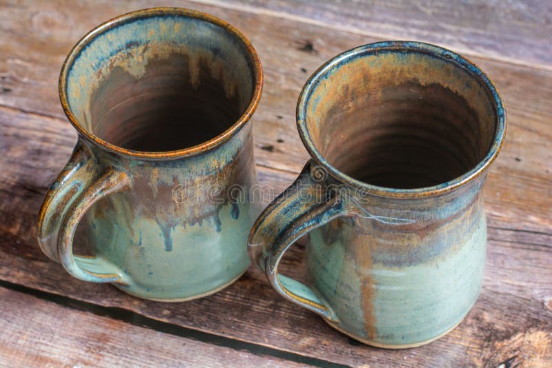 Deux Clay Mugs rustique sur un vieux plancher de panneau de grange image libre de droits Deux Clay Mugs rustique sur un vieux plancher de panneau de grange image libre de droits