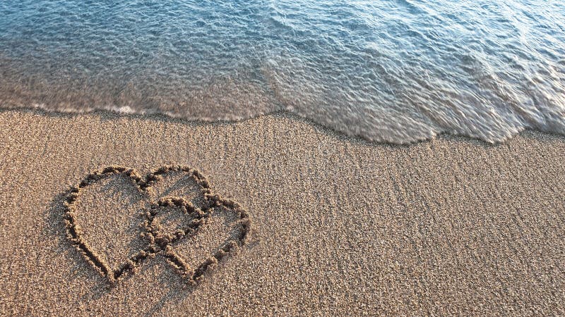 Two hearts painted on sand on the beach. Two hearts painted on sand on the beach.