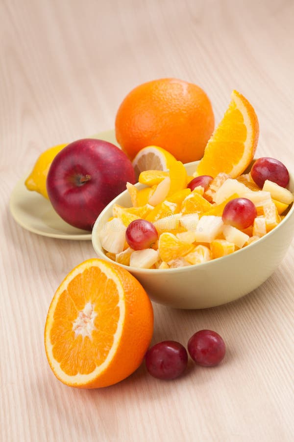 Deux cuvettes avec la salade de fruits sur la table en bois avec la moitié de l'orange image libre de droits Deux cuvettes avec la salade de fruits sur la table en bois avec la moitié de l'orange image libre de droits