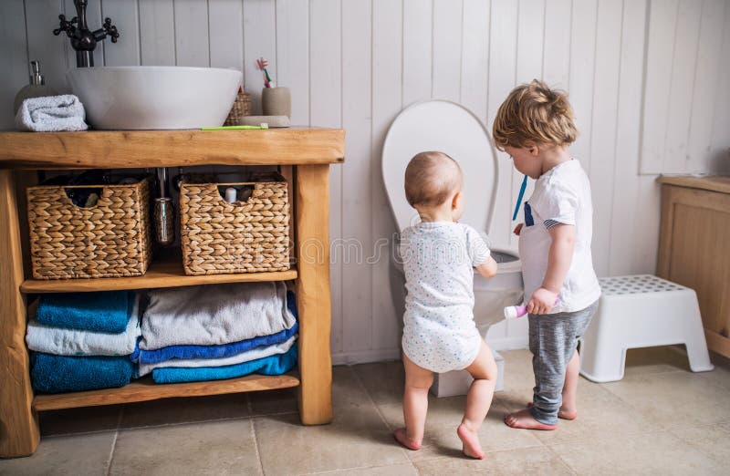 Deux enfants d'enfant en bas âge avec la brosse à dents se tenant prêt la toilette dans la salle de bains à la maison image stock Deux enfants d'enfant en bas âge avec la brosse à dents se tenant prêt la toilette dans la salle de bains à la maison image stock