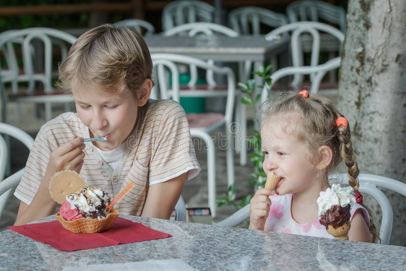 Deux enfants de mêmes parents mangeant le dessert dans le gelateria italien de barre de crème glacée photos libres de droits