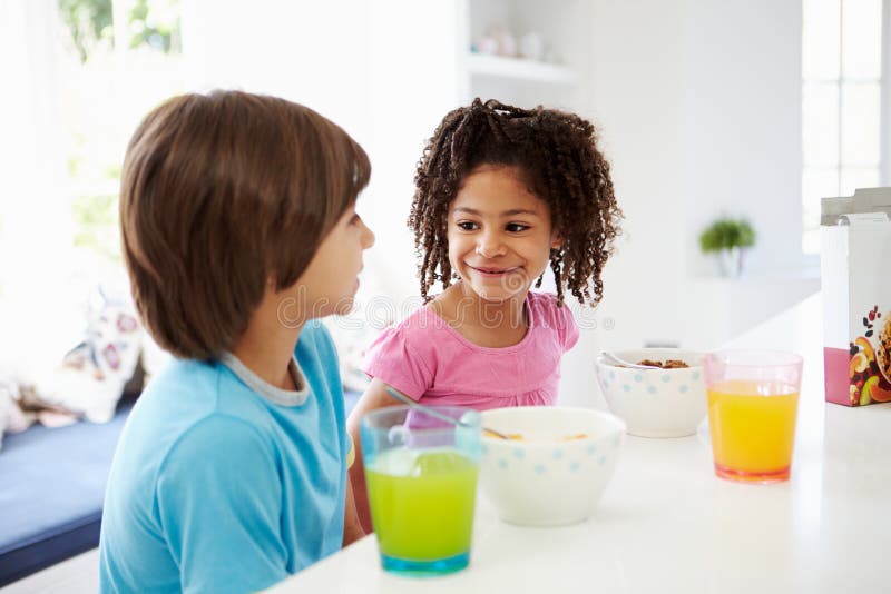 Deux enfants prenant le petit déjeuner dans la cuisine ensemble image stock Deux enfants prenant le petit déjeuner dans la cuisine ensemble image stock