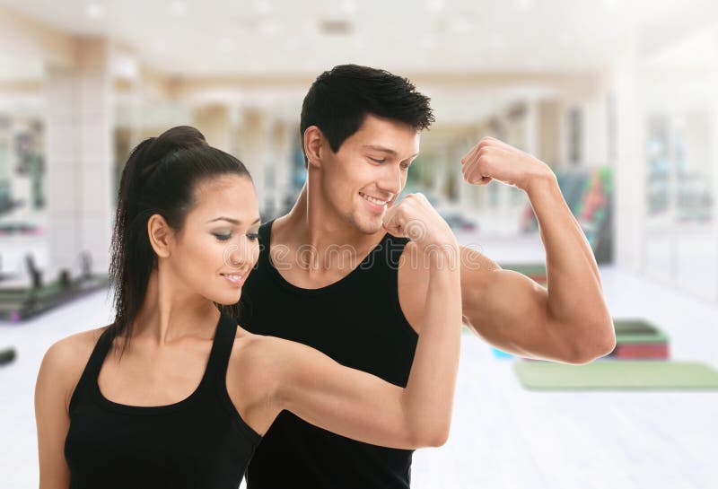 Deux entraîneurs folâtres dans le noir montrant le biceps photographie stock Deux entraîneurs folâtres dans le noir montrant le biceps photographie stock