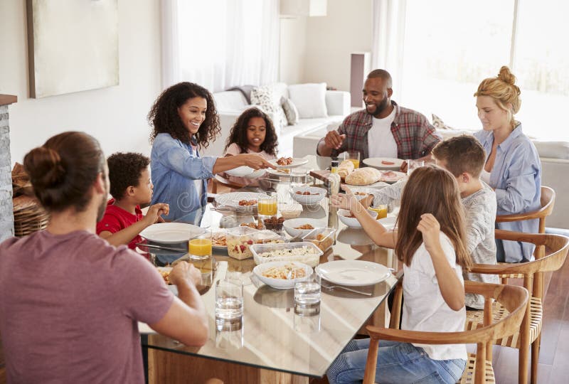 Deux familles appréciant le repas à la maison ensemble image libre de droits Deux familles appréciant le repas à la maison ensemble image libre de droits
