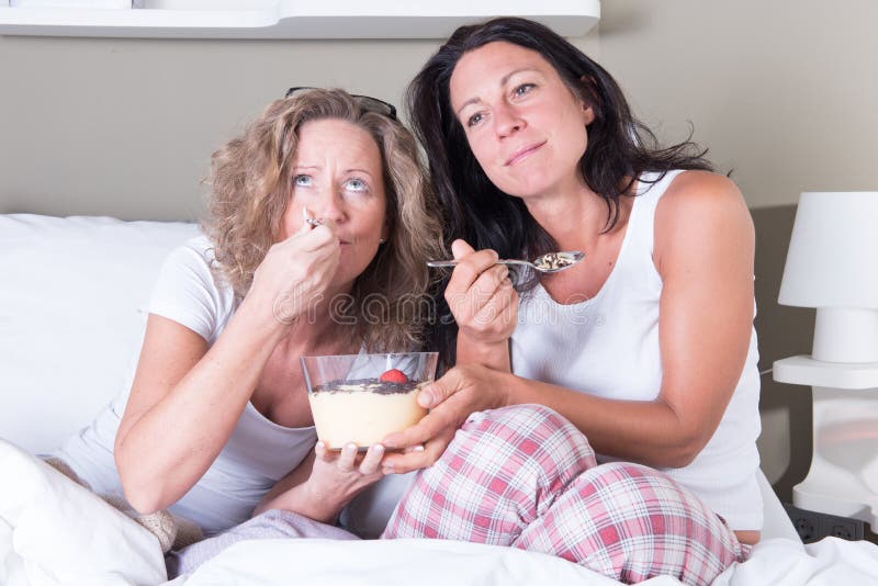 Deux femmes attirantes appréciant la soirée de leurs femmes dans le lit photographie stock Deux femmes attirantes appréciant la soirée de leurs femmes dans le lit photographie stock