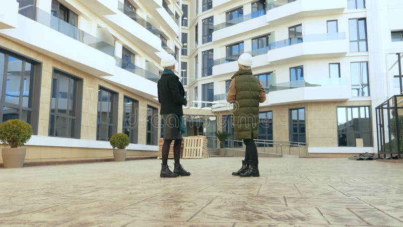 Deux femmes dans les casques blancs parlent au fond du bâtiment