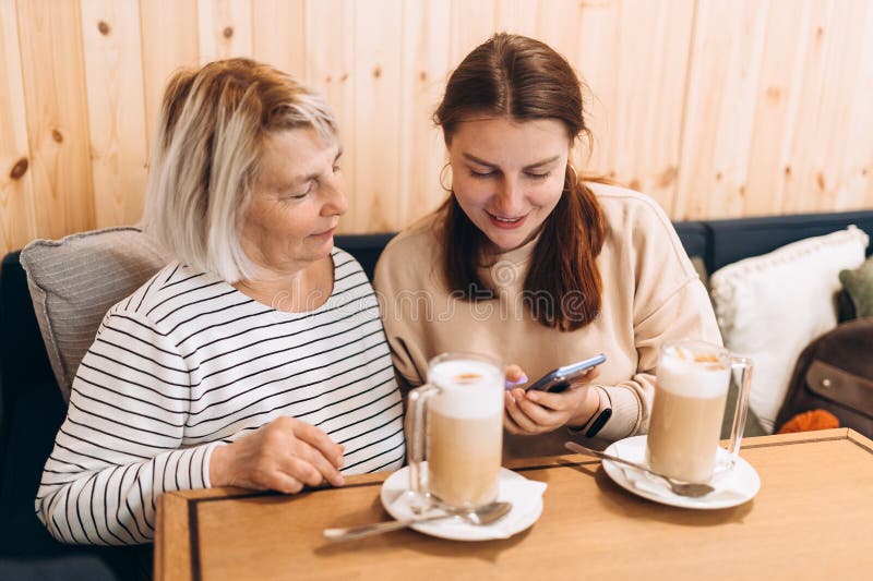 Two women sitting in a cafe, talking and drinking coffee. Female friends having coffee, smiling. Two women sitting in a cafe, talking and drinking coffee. Female friends having coffee, smiling