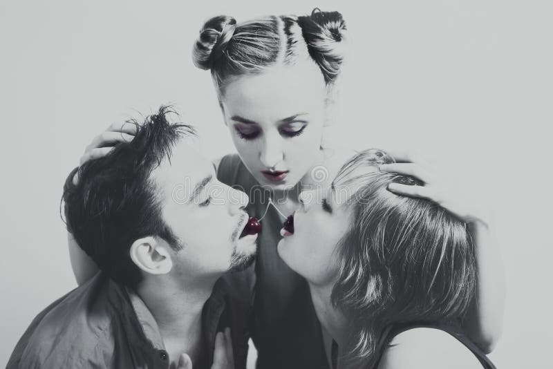 Deux femmes et un homme avec les cerises mûres rouges image stock Deux femmes et un homme avec les cerises mûres rouges image stock