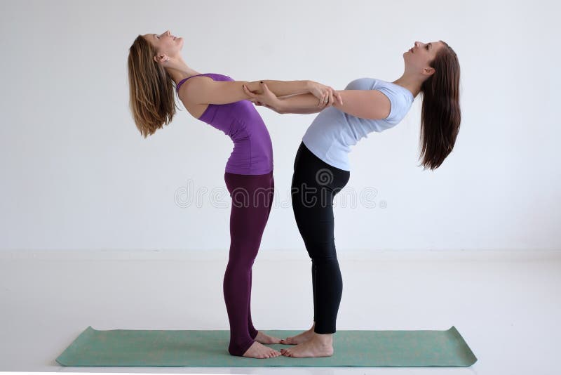 Deux femmes faisant des exercices de yoga, se tenant se pliants entre eux photos stock Deux femmes faisant des exercices de yoga, se tenant se pliants entre eux photos stock