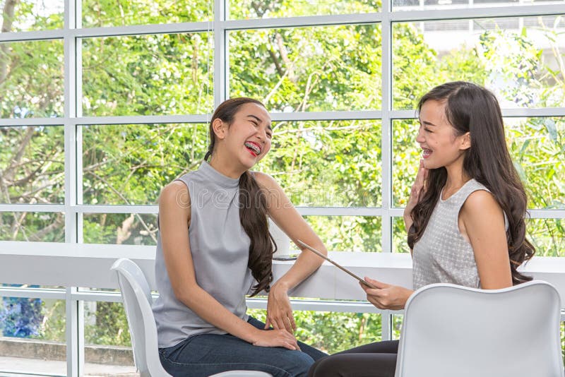 Deux femmes heureuses à l'aide du comprimé se reposant dans le café Deux meilleurs amis de jeunes femmes souriant utilisant un co photo stock