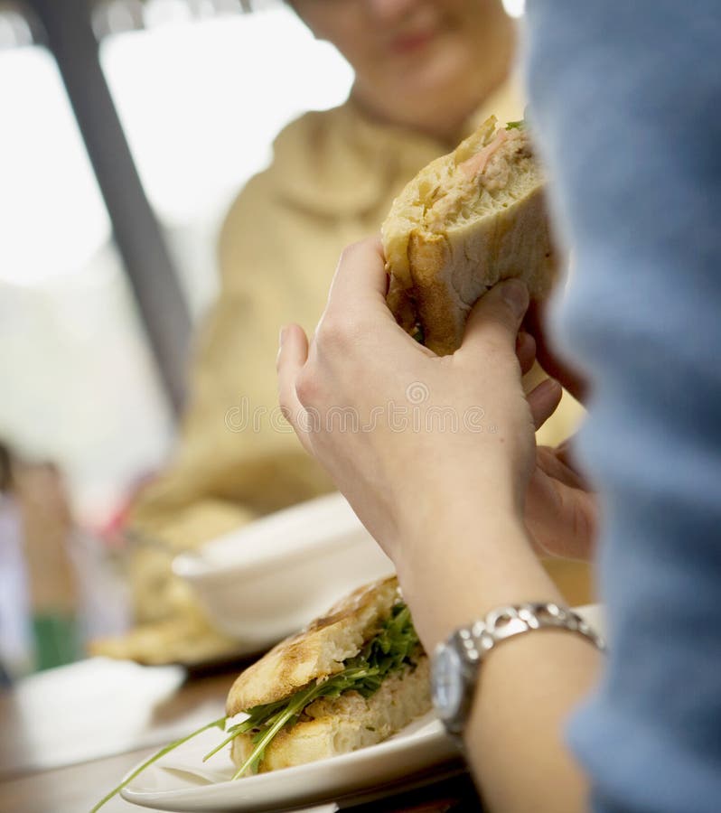 Two women having lunch at a cafe with sandwiches. Two women having lunch at a cafe with sandwiches