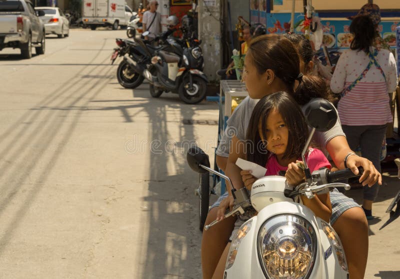 Deux femmes thaïlandaises avec une petite fille utilisaient une motocyclette photographie stock libre de droits Deux femmes thaïlandaises avec une petite fille utilisaient une motocyclette photographie stock libre de droits