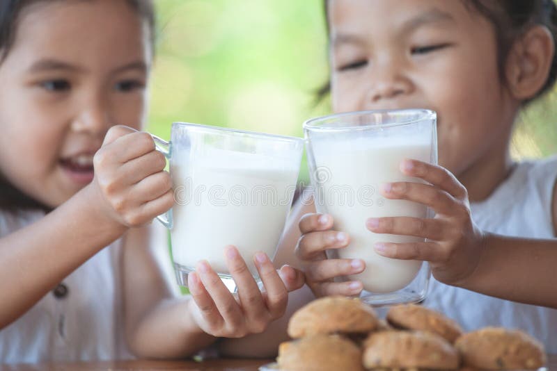 Deux filles asiatiques mignonnes de petit enfant tenant le verre de lait image libre de droits Deux filles asiatiques mignonnes de petit enfant tenant le verre de lait image libre de droits