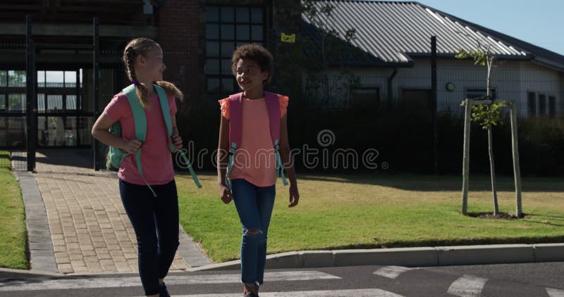 Deux filles avec des sacs d'école parlant en traversant la route clips vidéos