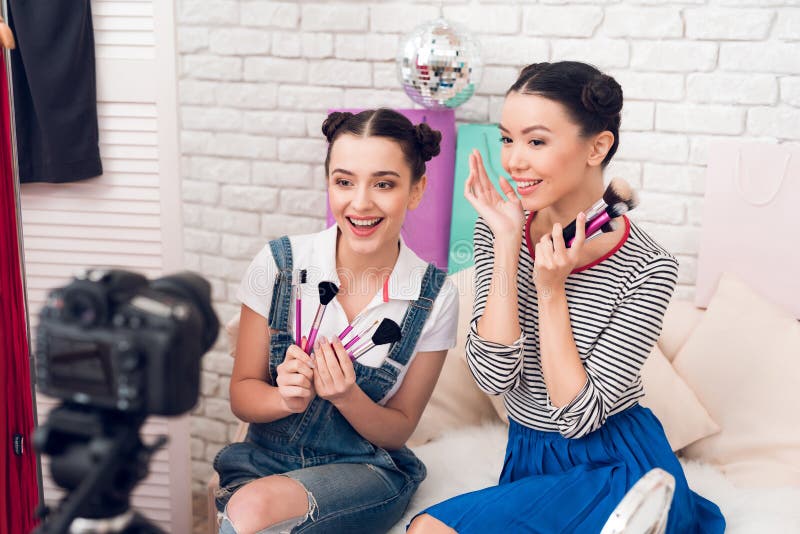 Deux filles de blogger de mode supportent beaucoup de brosses à l'appareil-photo image stock Deux filles de blogger de mode supportent beaucoup de brosses à l'appareil-photo image stock