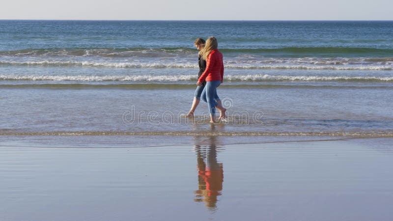 Deux filles marchent le long de la plage sablonneuse en Irlande du Nord un jour frais en automne