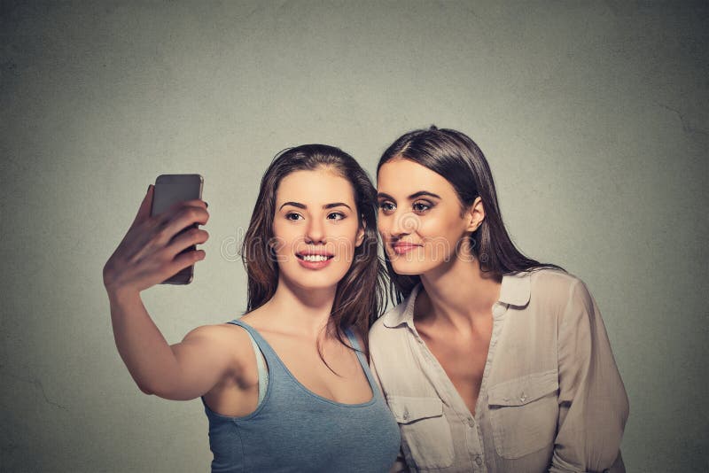 Deux filles prenant le selfie avec l'appareil-photo futé de téléphone photographie stock Deux filles prenant le selfie avec l'appareil-photo futé de téléphone photographie stock