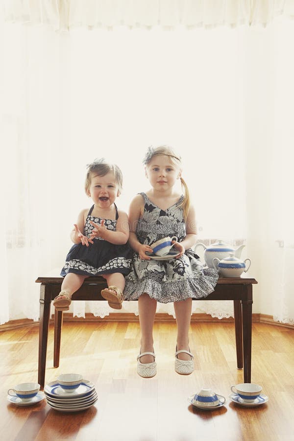 Deux filles sur le banc avec des paraboloïdes images stock Deux filles sur le banc avec des paraboloïdes images stock