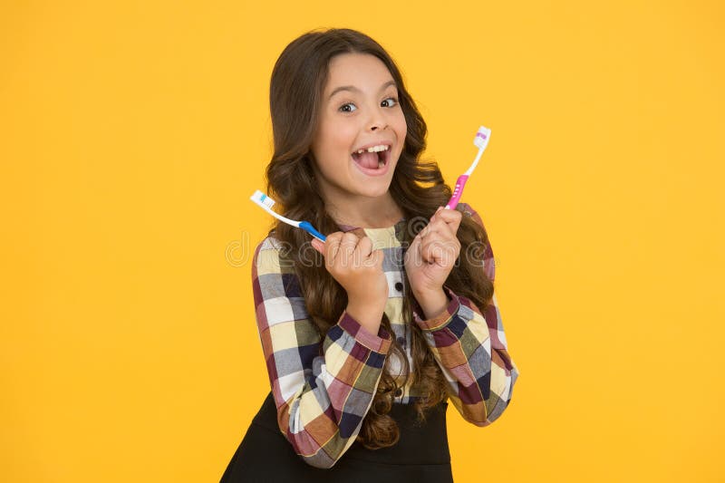 Twice faster. Child girl holds two toothbrushes. Child school girl smart kid happy face cares hygiene. Brush teeth concept. Teeth hygiene. Girl cute long hair holds toothbrushes yellow background. Twice faster. Child girl holds two toothbrushes. Child school girl smart kid happy face cares hygiene. Brush teeth concept. Teeth hygiene. Girl cute long hair holds toothbrushes yellow background.