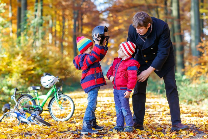 Deux garçons et père de petit enfant avec des bicyclettes en automne se garent photo stock Deux garçons et père de petit enfant avec des bicyclettes en automne se garent photo stock