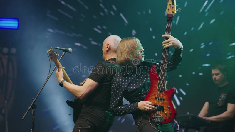 Deux guitaristes jouent ensemble sur scène en concert. les guitaristes du groupe de rock créent de l'humeur. mouvement lent banque de vidéos