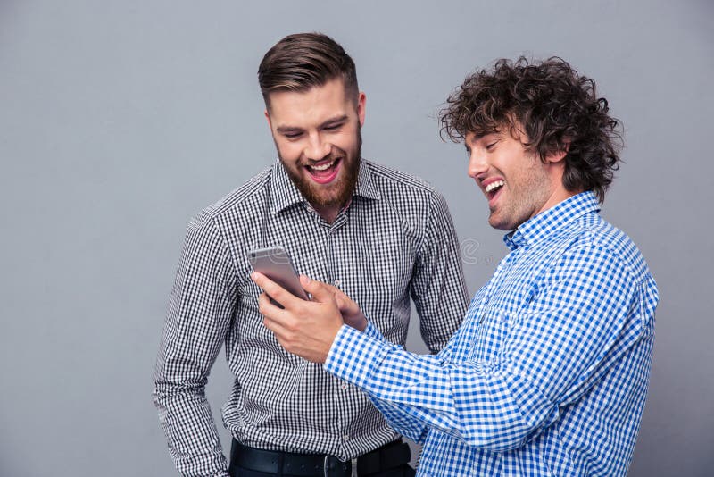Deux hommes riants à l'aide du smartphone photo stock Deux hommes riants à l'aide du smartphone photo stock