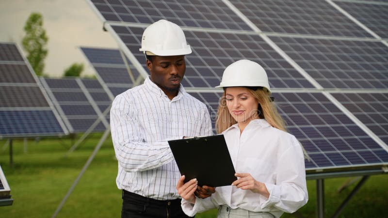 Deux ingénieurs divers travaillant dans une station de panneaux solaires clips vidéos
