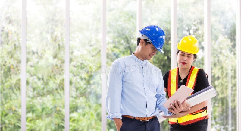Deux ingénieurs travaillant dehors avec un comprimé Deux travailleurs observent le plan de construction au bureau Affaires asiati image stock Deux ingénieurs travaillant dehors avec un comprimé Deux travailleurs observent le plan de construction au bureau Affaires asiati image stock