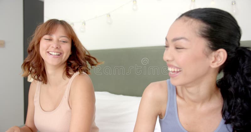 Deux jeunes amies biraciales rient ensemble sur un lit clips vidéos