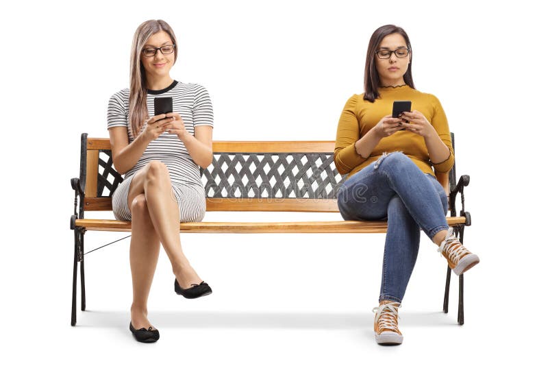 Deux jeunes femmes assises sur un banc et tapant sur des smartphones images libres de droits Deux jeunes femmes assises sur un banc et tapant sur des smartphones images libres de droits