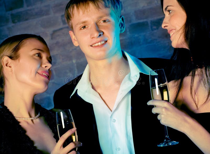 Deux jeunes femmes doux attirants et homme avec des glaces de champagne photos stock Deux jeunes femmes doux attirants et homme avec des glaces de champagne photos stock