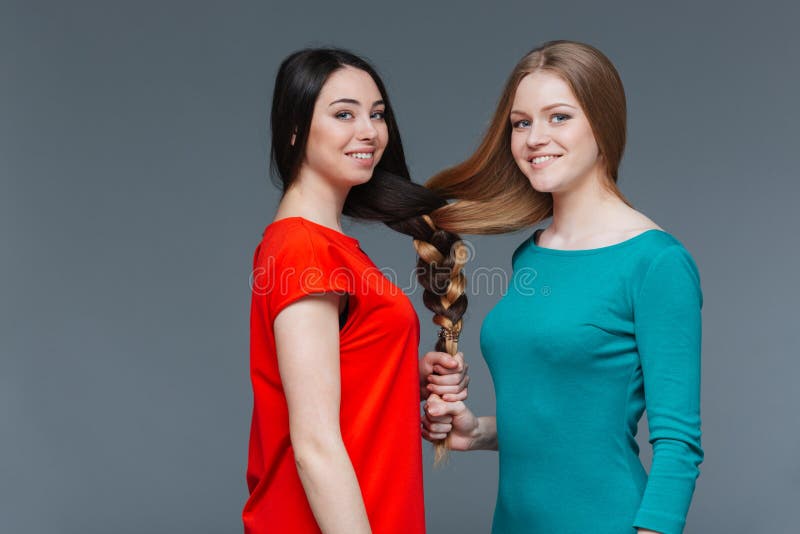 Deux jeunes femmes heureuses ont fait un brair avec leurs cheveux images stock Deux jeunes femmes heureuses ont fait un brair avec leurs cheveux images stock