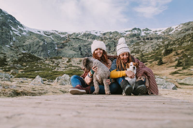 Deux jeunes femmes jouent avec leurs chiens au milieu du pré images stock Deux jeunes femmes jouent avec leurs chiens au milieu du pré images stock