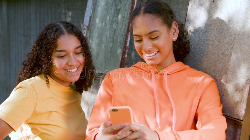 Deux jeunes filles afro-américaines souriantes jeunes femmes de la ville utilisant un téléphone portable pour les médias sociaux clips vidéos