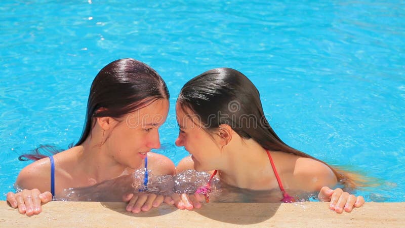 Deux jeunes filles parlant entre eux dans la piscine banque de vidéos