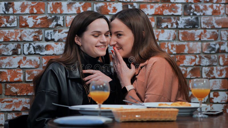 Two young girls gossiping sitting in a cafe. Two young girls gossiping sitting in a cafe