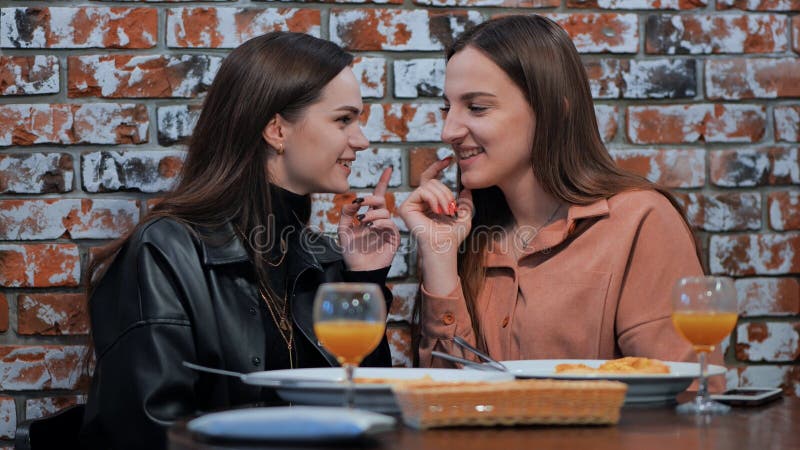 Two young girls gossiping sitting in a cafe. Two young girls gossiping sitting in a cafe