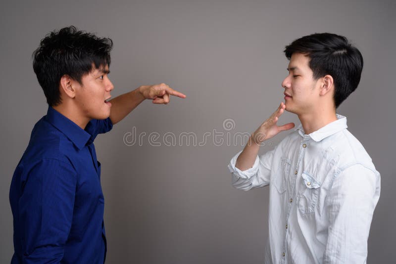 Deux jeunes hommes asiatiques beaux ayant l'argument photo libre de droits Deux jeunes hommes asiatiques beaux ayant l'argument photo libre de droits
