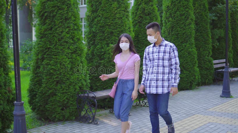Deux jeunes Ã©tudiants asiatiques portant un masque mÃ©dical sur le visage marchant dans la rue et parlant