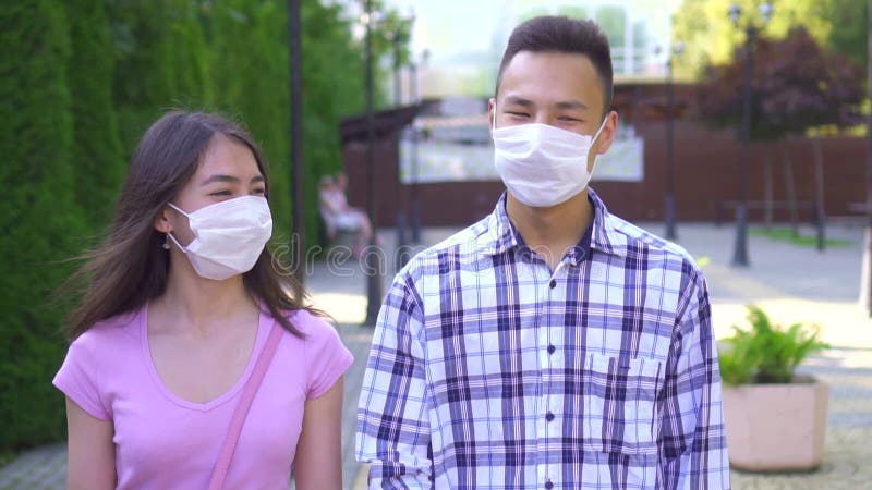 Deux jeunes étudiants asiatiques sur un masque médical, se baladant dans la rue et parlant de près lentement mo
