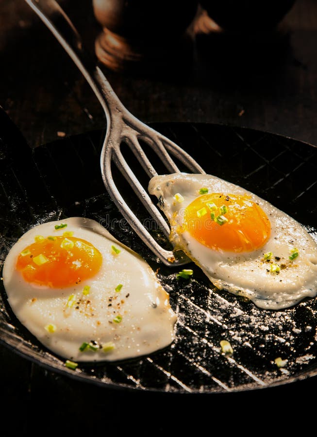 Two delicious free range fried eggs with dark yellow yolks seaoned with salt and aromatic herbs for a healthy breakfast and start to the day. Two delicious free range fried eggs with dark yellow yolks seaoned with salt and aromatic herbs for a healthy breakfast and start to the day