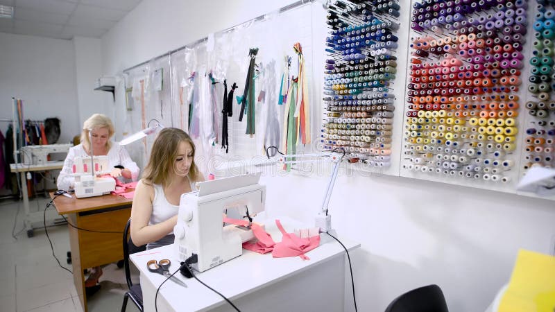 Deux ouvrières couturières féminines travaillant à la machine à coudre se reposant aux tables en travaillant le studio Couturière banque de vidéos