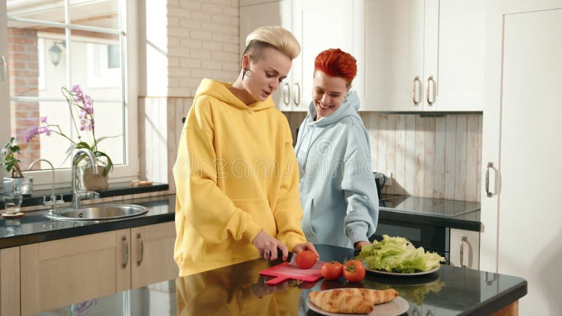Deux personnes cuisinent ensemble dans une cuisine moderne coupant des légumes collants et profitant du travail d'équipe banque de vidéos