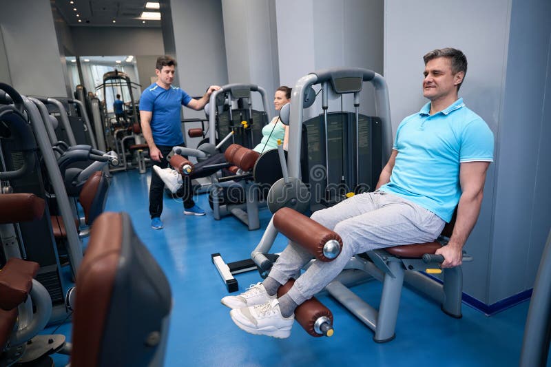 Deux personnes faisant de l'entraînement en bas de l'organisme supervisé par l'instructeur de fitness image libre de droits