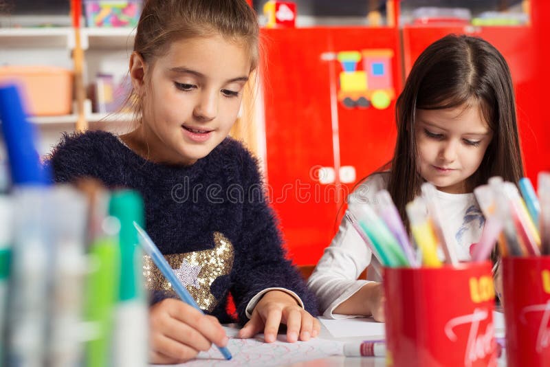 Deux petites filles dessinant sur le papier à la table photographie stock libre de droits Deux petites filles dessinant sur le papier à la table photographie stock libre de droits