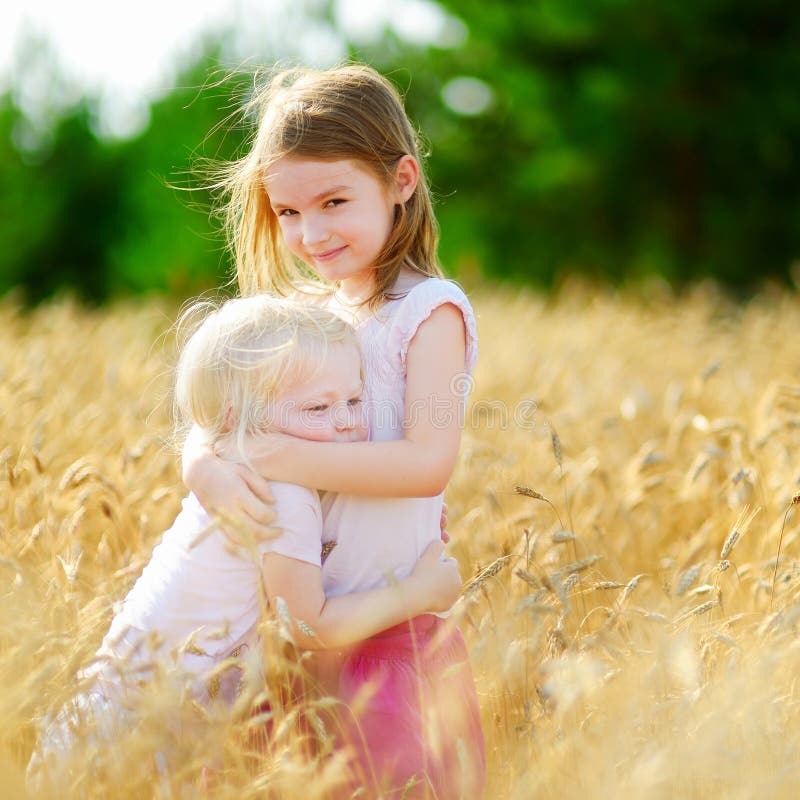 Deux petites soeurs dans le domaine de blé le jour d'été photographie stock libre de droits Deux petites soeurs dans le domaine de blé le jour d'été photographie stock libre de droits