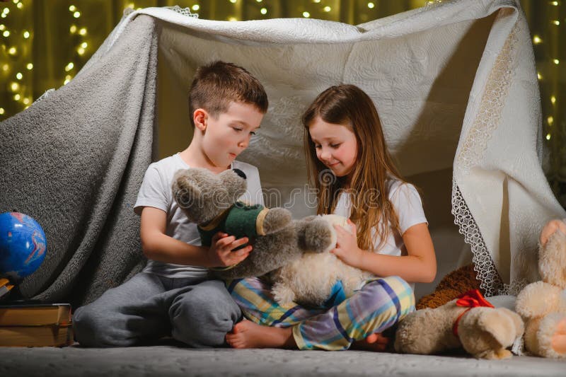 Deux Enfants Avec Une Lampe De Poche Lisent Un Livre Sous Une Couverture En  Guise De Tente