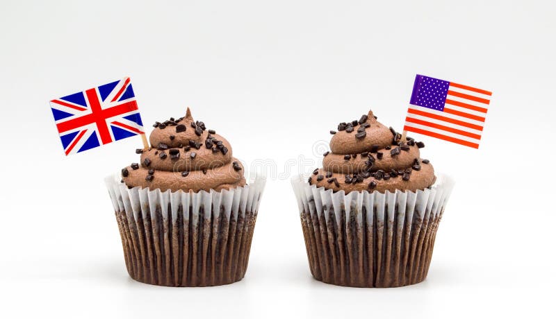 Deux petits g?teaux de remous de puce de chocolat avec le drapeau am?ricain tricolore et cure-dents britanniques de drapeau d'Uni image stock Deux petits g?teaux de remous de puce de chocolat avec le drapeau am?ricain tricolore et cure-dents britanniques de drapeau d'Uni image stock