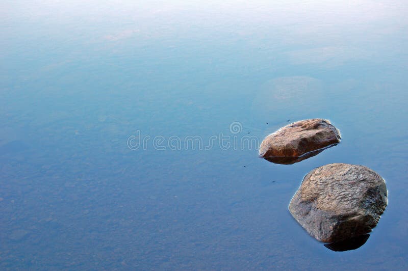 Two loneless stones in lake water. Two loneless stones in lake water