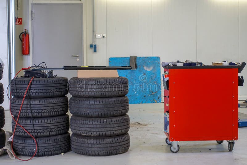 Deux piles des pneus de voiture et d'un chariot à outil image libre de droits Deux piles des pneus de voiture et d'un chariot à outil image libre de droits